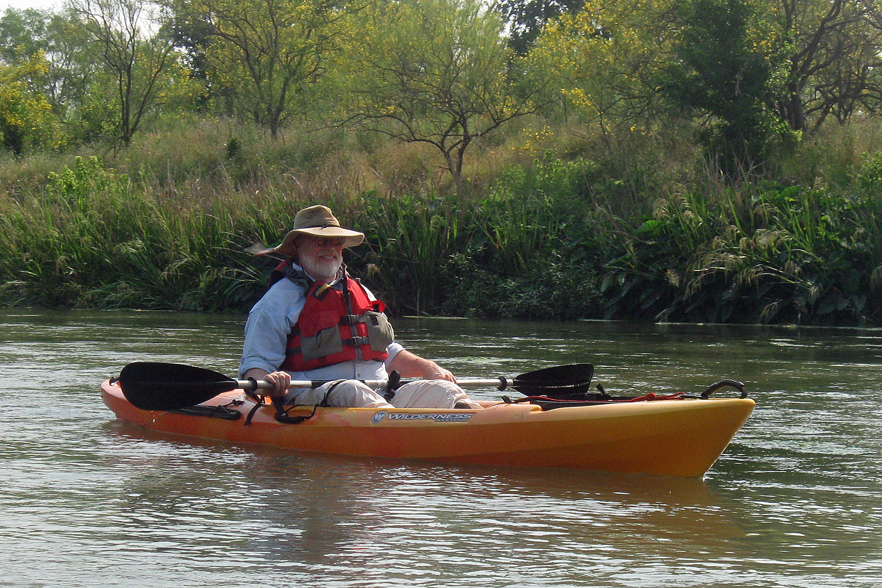 Photo of a man with a wide-brimmed hat and beard in a kayak.